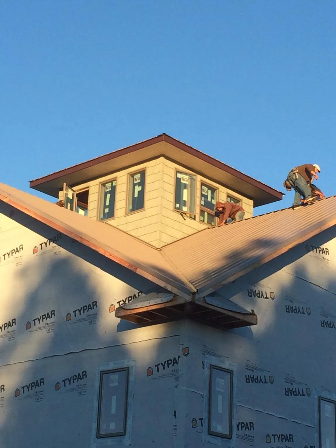 Roofers working around a rooftop cupola on a new metal roof at sunset — Roof Waterproofing in Holbrook by Roofing Brothers